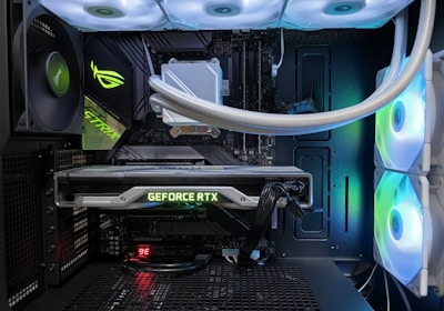 A high-end gaming or performance PC interior equipped with RGB lighting and multiple cooling fans. The graphics card prominently displayed is a GeForce RTX model, with branding visible. The setup includes neatly managed cables and a liquid cooling system.
